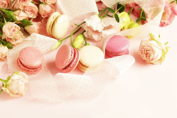 macaroons in pastel colors with flowers on a pale pink background.Holiday background.copy space