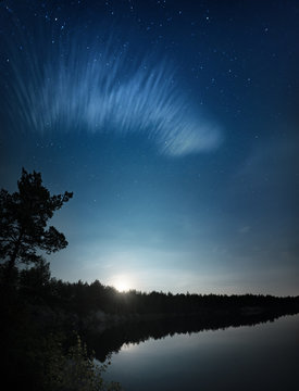 Lake at night with amazing starry sky, moon and clouds. Natural outddors travel dark background.