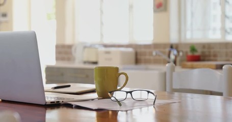 Laptop with documents, spectacle and coffee mug on a table 