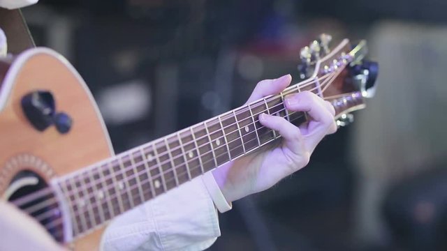 close-up of the musician's hands playing acoustic guitar at a concert, from playing the guitar vibrate strings