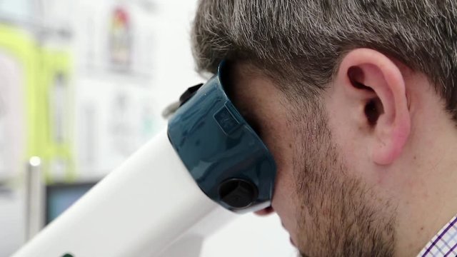 Man looks in apparatus for the treatment of spasm of accommodation, amblyopia and binocular vision disorders. Patient in ophthalmology clinic