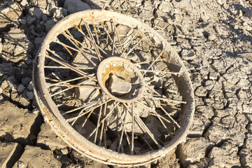 Old wheel on dry clay in empty lake, in Spain