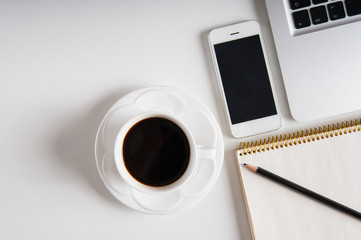 Notepad, laptop with pencil, smartphone and coffee cup on wood table. Flat lay.