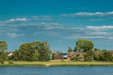 Obraz premium Belarusian Wooden House In Village Or Countryside Of Belarus With Lake Pond River