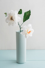 Open centered crepe paper dahlia in a vase on white