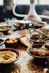 Young happy company of people is eating lebanon food and smokinh shisha. Lebanon cuisine. Traditional meze lunch