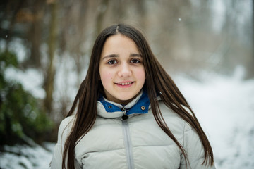 portrait of an 11-year-old girl outside under a snowfall, dressed in a down jacket, a windbreaker © Emanuele Capoferri