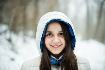 portrait of an 11-year-old girl outside under a snowfall, dressed in a down jacket, a windbreaker