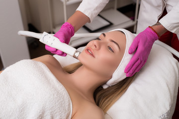 Be always young! Side-view portrait of a young woman with a towel on her head lying on a table getting a skin treatment in healthy beauty spa salon.