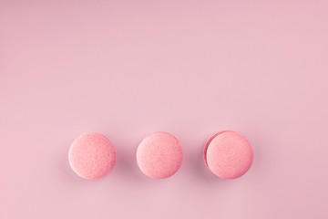 Top view of mini pink macaron on soft sweet pink paper background. Pink round macaron. popular sweets