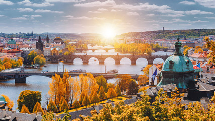 Fototapeta premium View to the historical bridges, Prague old town and Vltava river from popular view point in the Letna park (Letenske sady), beautiful autumn landscape in soft yellow light, Czech Republic