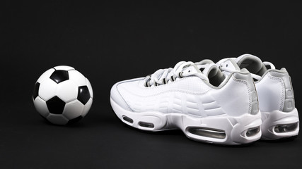 .white sneakers and ball on a black background
