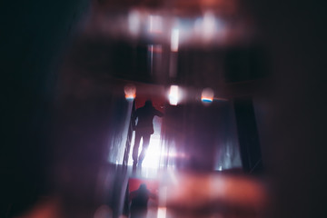 Rear view of the silhouette of a businessman in a formal suit moving away in a dark office corridor...