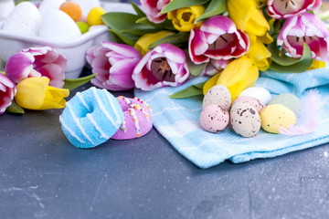 A bouquet of fresh spring tulips of pink and yellow color. Buds. Eggs for Easter are different colors. Sweets as a gift.