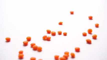 Red lentils falling against white background