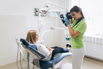 Dentist making shots of patients smile after treatment. Special camera with flash ring shadowless.