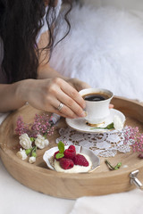 Morning coffee and flowers. Romantic breakfast in bed. A wooden tray and a cup of fragrant coffee. Home cosiness. Light background