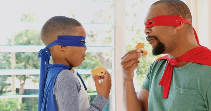 Father and son eating muffins while pretending to be superhero 