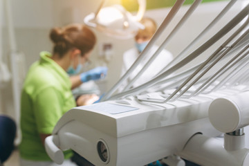 Dental accessories and two dentists near a patient on background in a clinic. Work process.