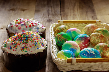 Two hot cross buns and Easter eggs are on the table from old wooden boards