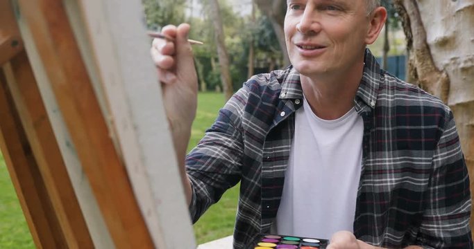 Man painting on canvas in the garden 