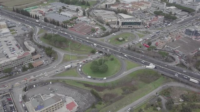 Aerial view of a series of highway ramps for immission or exit from the highway at high speed. So many cars, motorcycles, trucks are running on this road near a big city and an industrial area.