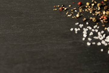  Coarse salt crystals and peppercorns on dark slate background - low angle, selective focus