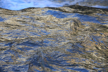 background of colorful and iridescent reflections on the surface of running water