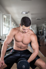Obraz premium Young attractive adult man exercising and doing weight lifting at fitness gym. Sport training indoors.