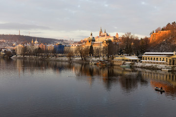 Fototapeta premium Sunny snowy early morning Prague Lesser Town with gothic Castle above River Vltava, Czech republic