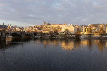 Sunny snowy early morning Prague Lesser Town with gothic Castle above River Vltava, Czech republic