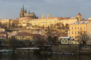 Obraz premium Sunny snowy early morning Prague Lesser Town with gothic Castle above River Vltava, Czech republic