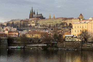 Sunny snowy early morning Prague Lesser Town with gothic Castle above River Vltava, Czech republic