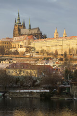 Fototapeta premium Sunny snowy early morning Prague Lesser Town with gothic Castle above River Vltava, Czech republic