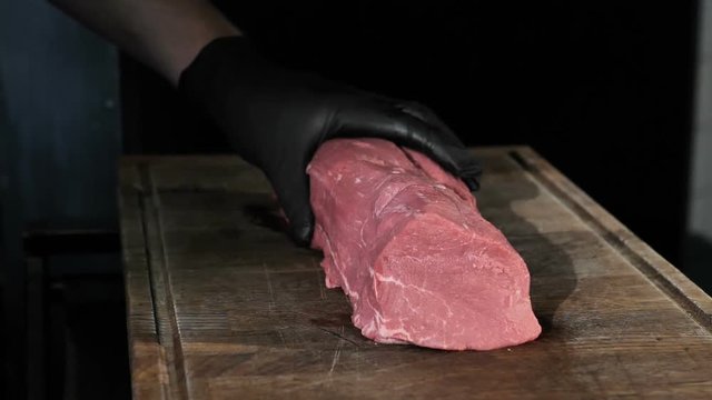 chef chefs cut a piece of meat in black gloves