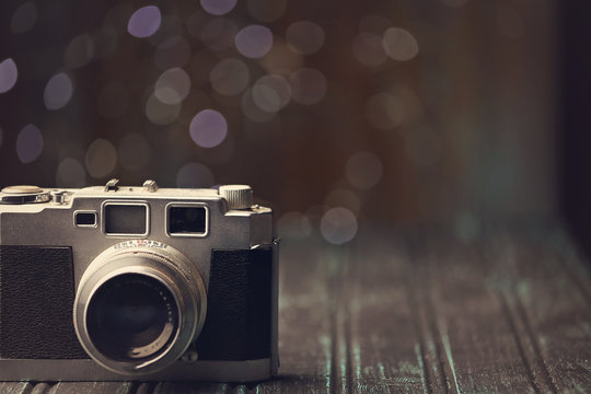 Old retro camera with bokeh background, silver and black body.