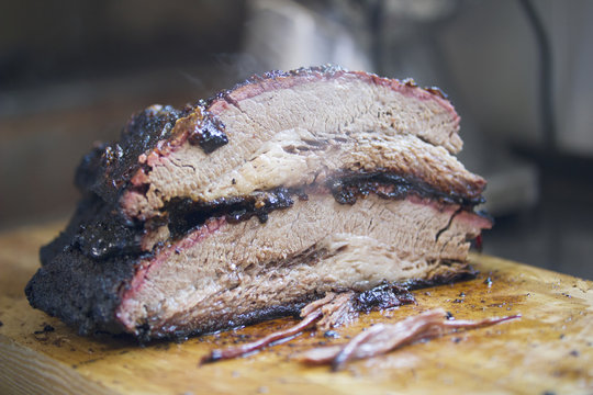 Two large pieces of smoked brisket meat on a wooden board