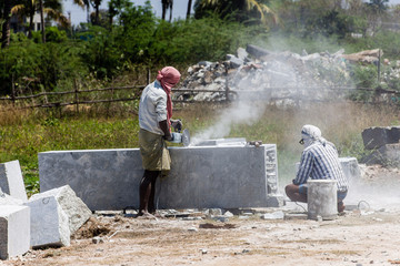 Sculptors cutting a piece of rock to make sculptures, in Kancheepuram, India