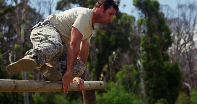 Military solider running over hurdles during obstacle course 