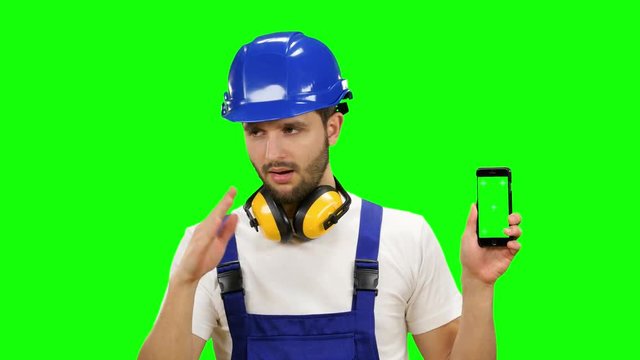Engineer is holding a phone in his hand and showing his finger down. Green screen. Mock up