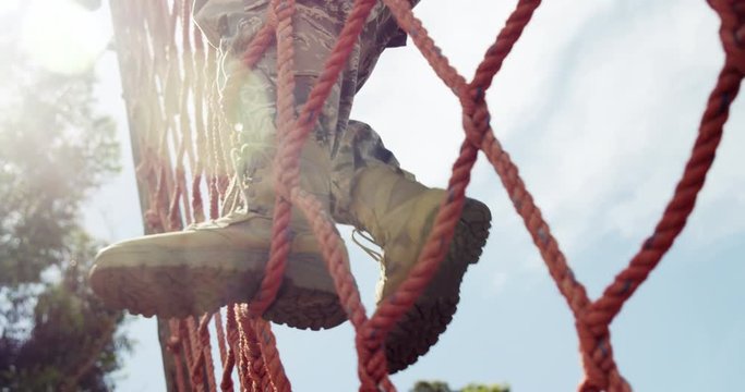 Military soldier climbing a net during obstacle course 