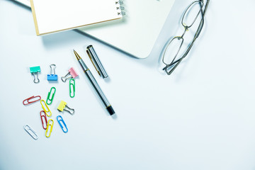 Top view of laptop, blank notebook, paper clips  and smart phone with white background and copy space.