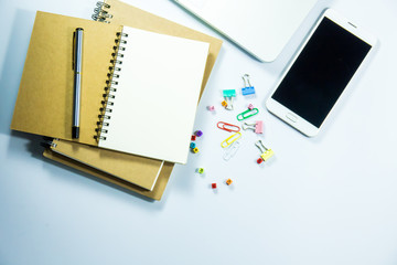 Top view of laptop, blank notebook, paper clips  and smart phone with white background and copy space.