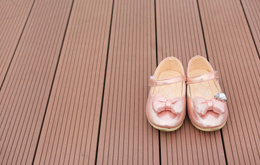 Pair of fashion princess shoes on wood plank background. Baby shoes.