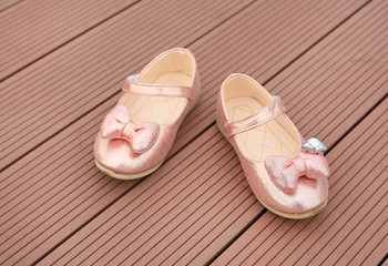 Pair of fashion princess shoes on wood plank background. Baby shoes.
