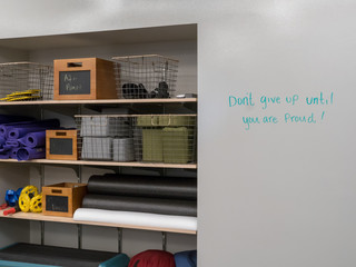 Shelf of work out equipment in modern gym with motivational "Don't give up" message on whiteboard