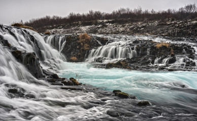 The Aquamarine Bruarfoss Waterfall of Iceland Meanders over Rocks on a Cloudy Day