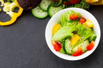 Fresh vegetable salad on balck background, top view