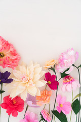 Crepe paper flowers on white wooden background