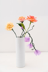 Bouquet of crepe paper roses and sweet peas in a vase on white